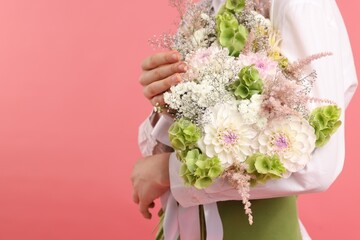 Florist with beautiful bouquet of flowers on pink background, closeup. Space for text