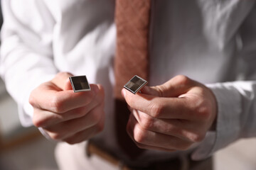 Man with cufflinks getting ready indoors, closeup