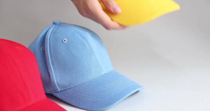 Woman taking yellow baseball cap on grey background, closeup