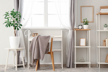 Interior of office with workplace, chair, houseplants and shelving units
