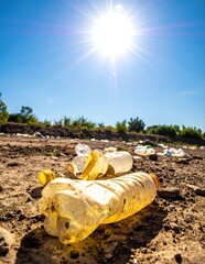 A vibrant yellow plastic bottle rests on the ground, its smooth surface reflecting sunlight, surrounded by scattered leaves and twigs.