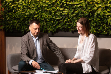 Two business partners laughing together while discussing documents in a modern office. Friendly...