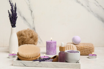 Beautiful composition with bottle of lavender oil, massage body brush and sea salt on tile background