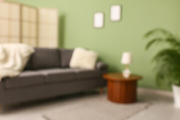 Cozy sofa and coffee table with lamp in living room. Blurred view