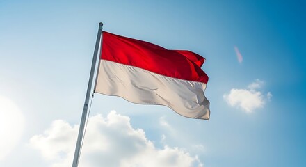 Indonesian flag waving against a blue sky with clouds