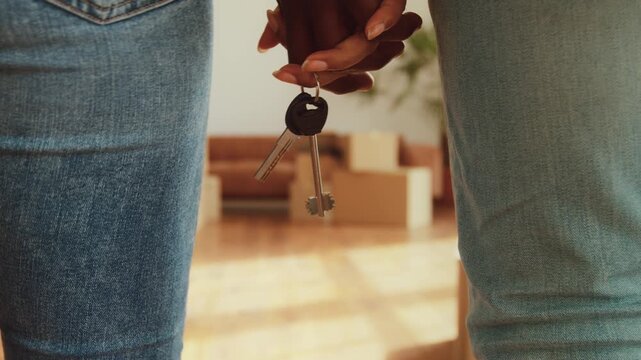 A family is excitedly preparing to move into a new apartment. Boxes are scattered around the bright space as new keys are held, symbolizing their fresh start in a new home.