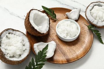 Wooden tray and bowl with natural coconut oil on marble background, closeup
