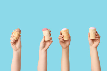 Female hands with different sweet ice-cream in waffle cups on blue background