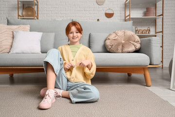 Teenage girl buttoning up yellow cardigan at home