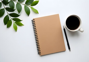Beige notebook, coffee cup, and green leaves on white surface