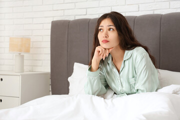 Morning of thoughtful young Asian woman in bedroom