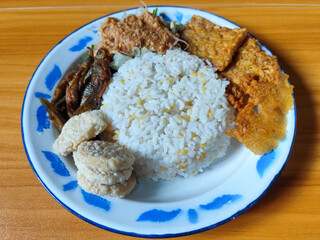 Nasi pecel or sego pecel is a typical Javanese Indonesian dish served with pecel sauce, which can be added with vegetables, peyek, fish, crackers, tempeh and other side dishes.