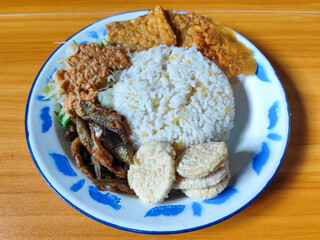 Nasi pecel or sego pecel is a typical Javanese Indonesian dish served with pecel sauce, which can be added with vegetables, peyek, fish, crackers, tempeh and other side dishes.