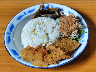 Nasi pecel or sego pecel is a typical Javanese Indonesian dish served with pecel sauce, which can be added with vegetables, peyek, fish, crackers, tempeh and other side dishes.