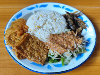 Nasi pecel or sego pecel is a typical Javanese Indonesian dish served with pecel sauce, which can be added with vegetables, peyek, fish, crackers, tempeh and other side dishes.