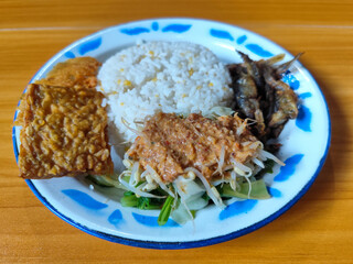 Nasi pecel or sego pecel is a typical Javanese Indonesian dish served with pecel sauce, which can be added with vegetables, peyek, fish, crackers, tempeh and other side dishes.