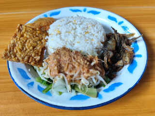 Nasi pecel or sego pecel is a typical Javanese Indonesian dish served with pecel sauce, which can be added with vegetables, peyek, fish, crackers, tempeh and other side dishes.