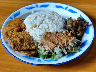 Nasi pecel or sego pecel is a typical Javanese Indonesian dish served with pecel sauce, which can be added with vegetables, peyek, fish, crackers, tempeh and other side dishes.
