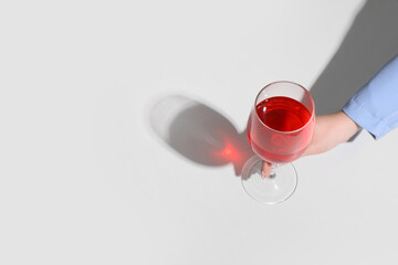 Female hand with glass of red wine on white background