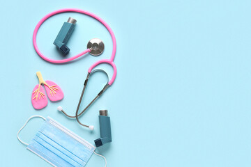 Asthma inhalers with stethoscope, lungs figurine and medical mask on blue background