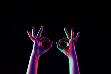 Obraz premium Toned female hands showing OK on dark background