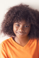 Portrait of happy african american girl smiling to camera. A cheerful young girl with curly black hair is smiling broadly showing her teeth on white background. Natural emotion kid.
