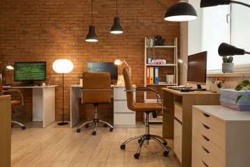 Interior of programmer's office with desks and glowing lamps in evening
