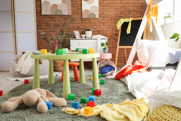 Interior of messy children's room with bed, scattered clothes and toys