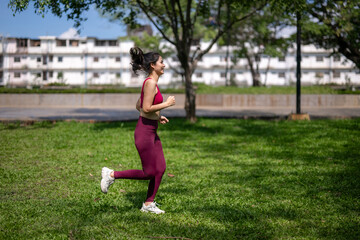 A woman is running in a park with a smile on her face