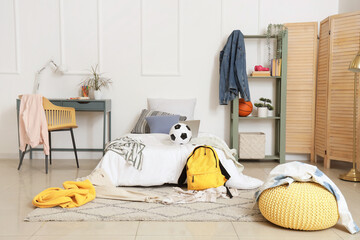Interior of messy children's room with bed, shelf unit and table