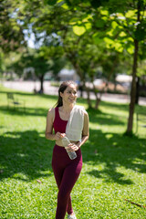 A woman is walking in a park with a bottle of water in her hand