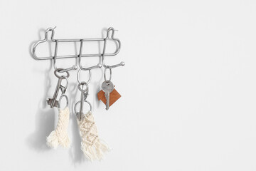Holder with keys hanging on white wall, closeup