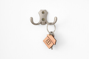 Holder with key hanging on white wall, closeup