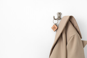 Holder with key and clothes hanging on white wall, closeup