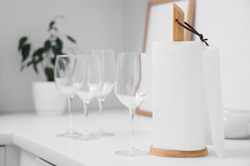 Roll of paper towels near glasses on table in kitchen