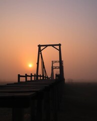 Obraz premium Cinematic photograph of an old wooden bridge at sunset. Soft haze, smooth color gradients, soft focus, hazy background, muted sunset tones.