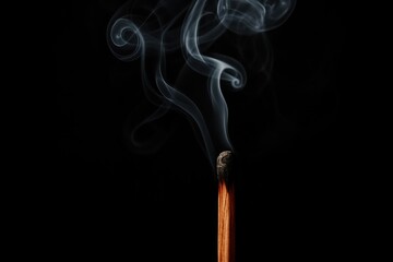 Vintage wooden matchstick with rising smoke tendrils against charcoal black backdrop creating mysterious ambiance