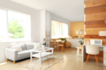 Blurred view of light room with table and sofa near window