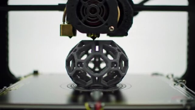 A 3D printer creating a hollow, geometrically complex sphere on a flat surface, against a stark white background