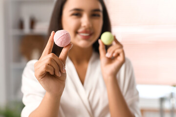 Pretty young woman holding bath bombs in bathroom