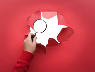 magnifying glass inspecting ripped red paper.