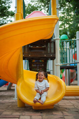 happy toddler baby girl sliding and playing at playground