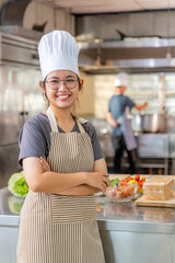 Young Female Chef Smiling in Professional Kitchen with Arms Crossed
