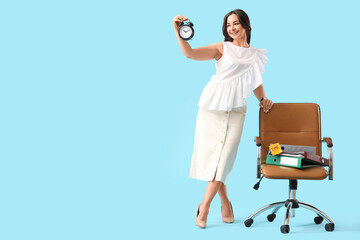 Businesswoman with alarm clock near chair on blue background. Time management concept