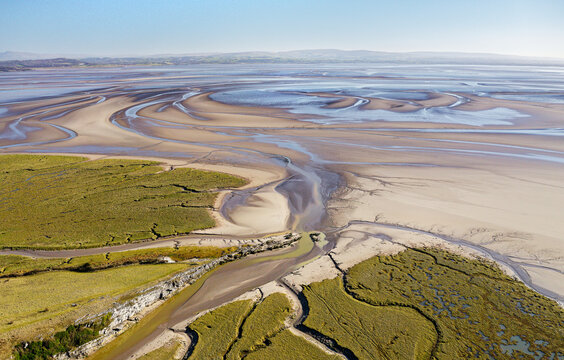 East from Humphrey Head over tidal marsh and mudflats where the River Kent estuary enters north end of Morecambe Bay, Cumbria. Aerial