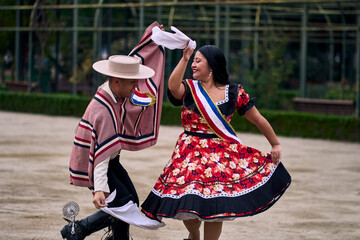 Obraz premium Portrait of a smiling young couple dressed as Chilean huasos, joyfully dancing cueca outdoors. Traditional Chilean dance. Chilean traditions, celebrations.