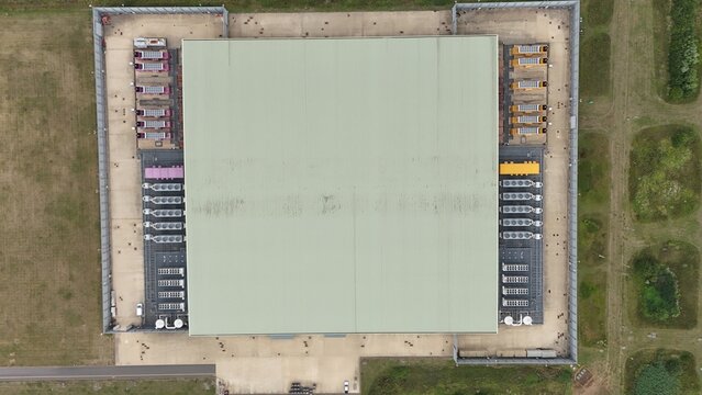 Aerial top down view of large futuristic cutting edge technology data center in England, with cooling fans and turbines, quantum computing and data storage. - Powered by Adobe