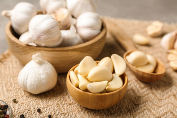 Wooden bowls with fresh garlics and peppercorns on grey background, closeup