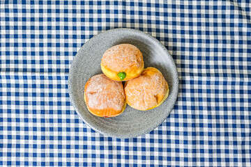 Top view of three bomboloni doughnut with strawberry, pineapple and matcha filling on grey or gray plate. homemade. Italian stuffed donuts. close up. Isolated on napkin background. High angle. Above.