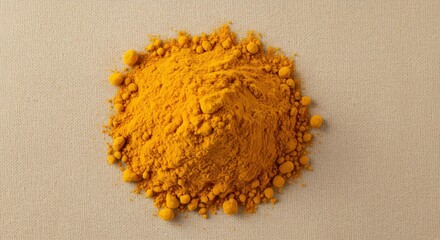 Pile of vibrant yellow turmeric powder on a light beige background
